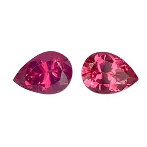 Two faceted red-pink gemstones (likely rubies) shown from a close-up angle with multiple reflective facets. Alternative: two magenta-cut gemstones.