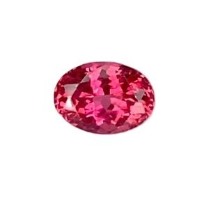 Round pink faceted gemstone (ruby) on a white background, close-up view
