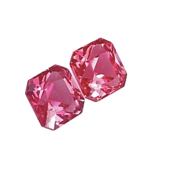 Close-up of faceted pink gemstones arranged along a curved line against a white background, showcasing their sparkle and facets.