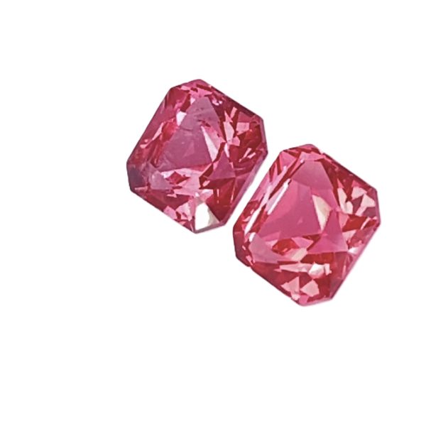 Close-up of faceted pink crystals arranged diagonally on a white background, showing their sharp geometric faces.