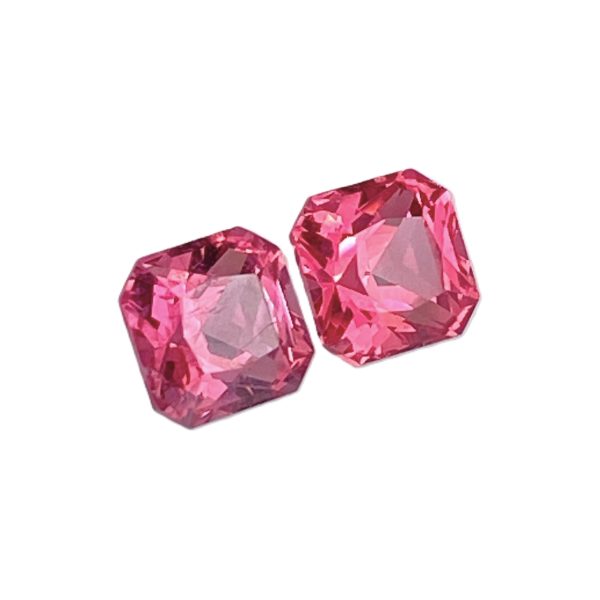 Cluster of pink faceted gemstones with angular cuts and light reflections.