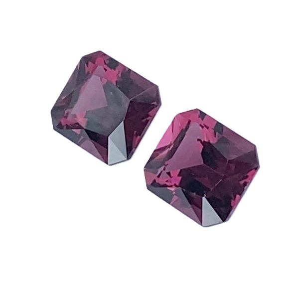 10_3 - GEMWORLD LTD Two faceted purple-pink gemstones with angular cuts on a white background, viewed from above or the side.