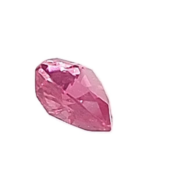 Close-up of a faceted pink gemstone on a white background, showing its angular facets and reflections.