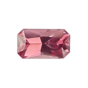 Close-up of a pink, faceted gemstone with multiple cut facets against a white background.