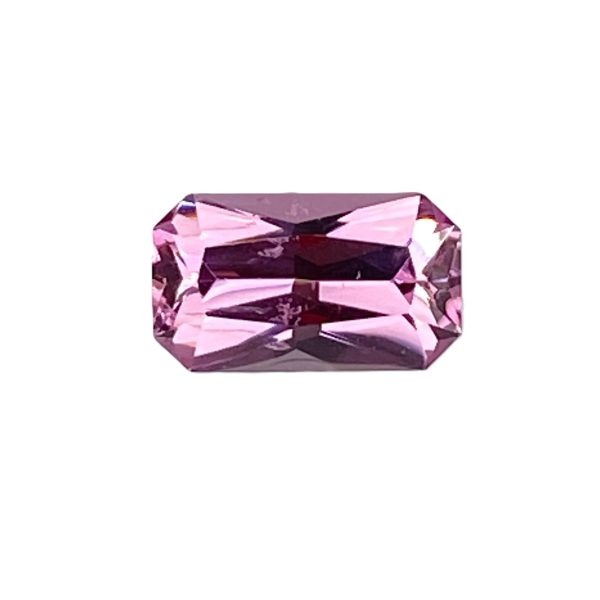 Fspin 239_2 - GEMWORLD LTD Close-up of a faceted pink-purple gemstone on a white background, showing angular facets and a square-ish octagonal shape.