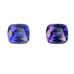 Two purple faceted gemstones placed side by side on a white background.