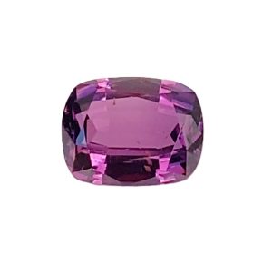 Close-up of an oval, purple faceted gemstone with pink highlights on a white background.