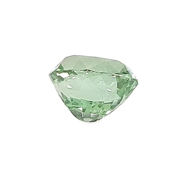 Green faceted gemstone, close-up showing multiple facets and a pale hue