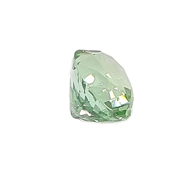 Close-up of a pale green faceted emerald gemstone.