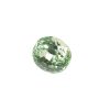 Close-up of a green faceted disco ball with reflective squares against a white background, showing its texture and facets.