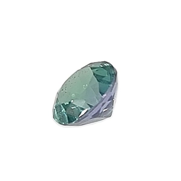 Close-up of a teal-green faceted gemstone with light reflections on its surfaces