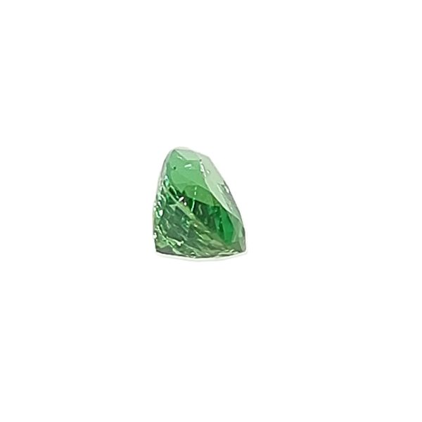 Close-up of a faceted emerald-green gemstone cut into a tapered teardrop shape on a white background.