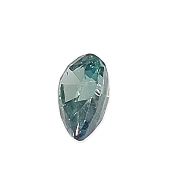 Korn 19_2 - GEMWORLD LTD Faceted teal gemstone/crystal with a pale blue-green color and elongated prism shape, set against a white background.