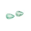 Several green, rough gemstones scattered on a white background, resembling emeralds/berries in shape and color.