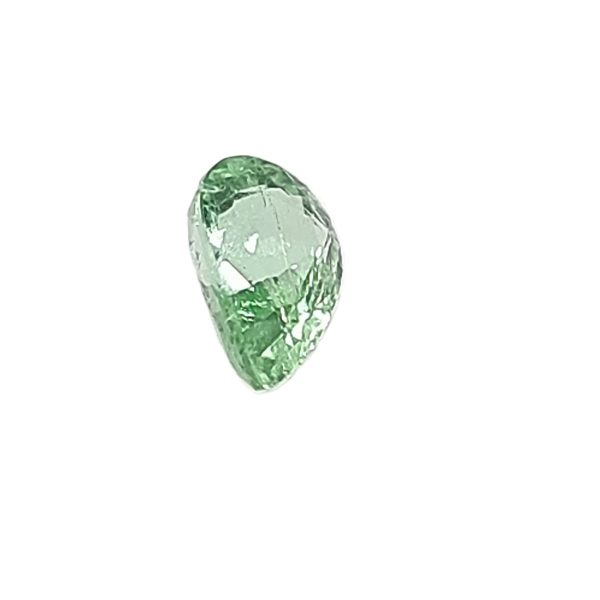 Partial green crystal gemstone with faceted, reflective surfaces on a white background, shown from above partially.