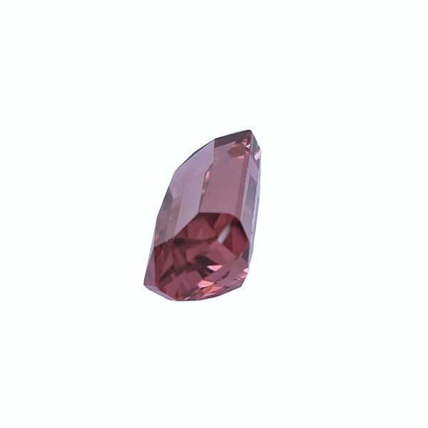 Tour 129_2 - GEMWORLD LTD Close-up of a pink faceted gemstone crystal against a pale background, showing brilliance and facets.