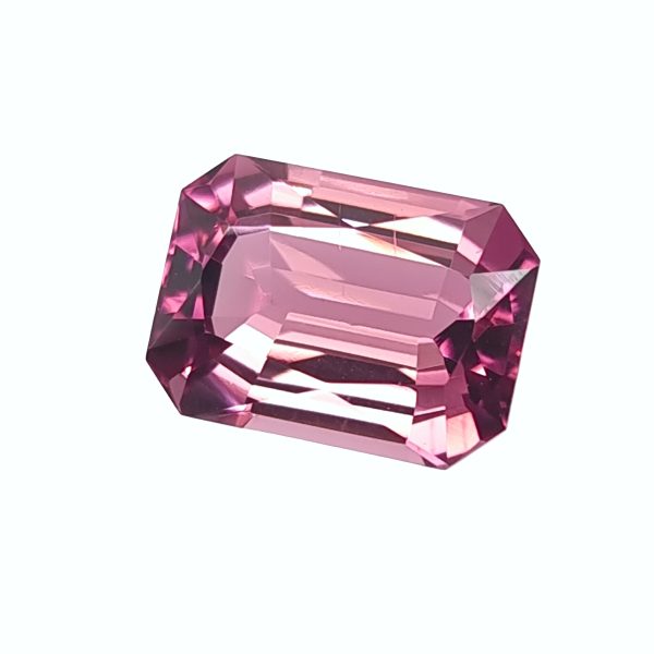 Close-up of a pink faceted gemstone with angular, reflective facets.