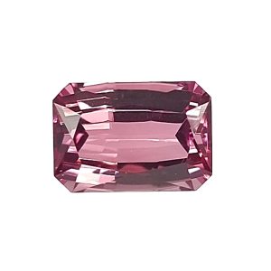 Close-up of a pink-red faceted gemstone with an octagonal cut on a white background.