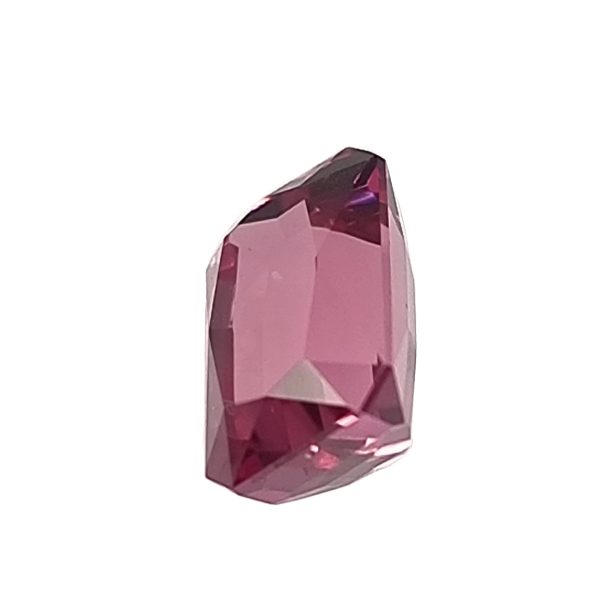 Faceted pink gemstone with sharp edges set against a white background, close-up view