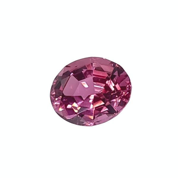 Close-up of a faceted red gemstone (ruby) against a white background with light reflections on the facets.
