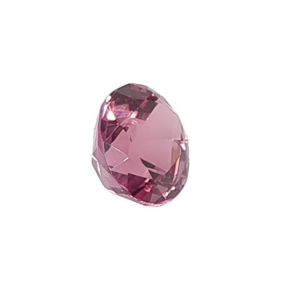 Pink faceted gemstone in an oval cut against a white background, showing light reflections on the facets, close-up view