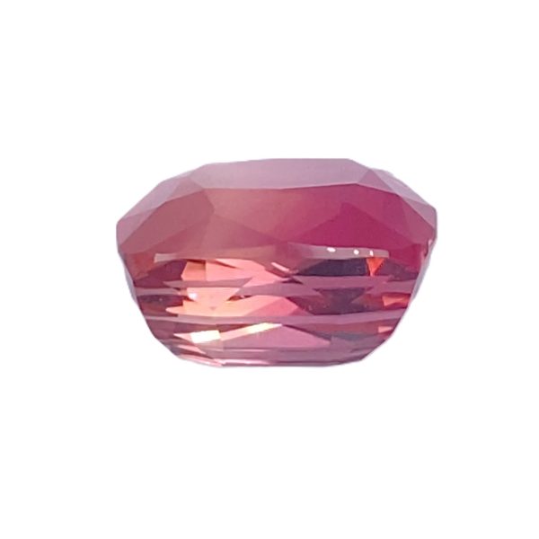 Tour 2_6 - GEMWORLD LTD Close-up of a faceted pink gemstone on a white background, showing multiple triangular facets and a rounded bottom edge.