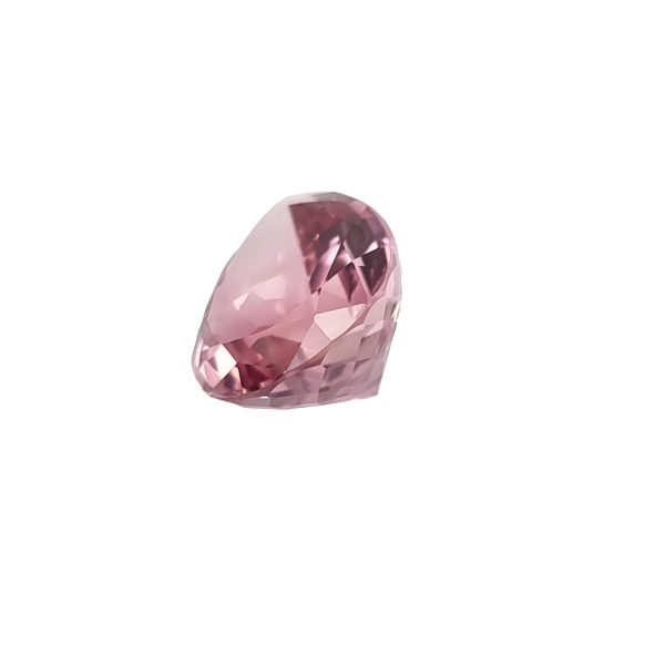 Close-up of a pink faceted gemstone with sparkling facets catching the light on a white background.